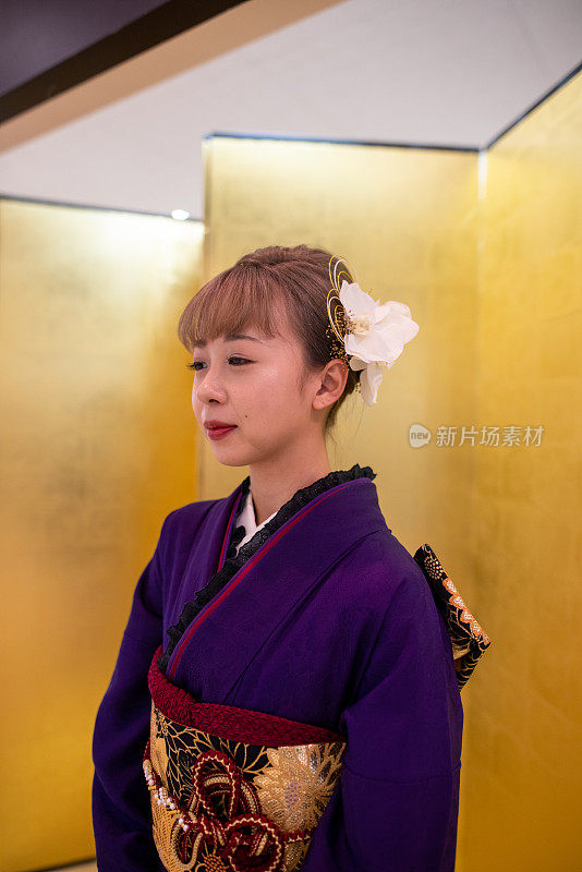 身着Furisode和服的日本妇女站在“Seijin Shiki”成人礼的金色“Byo-bu”折叠屏风前的肖像